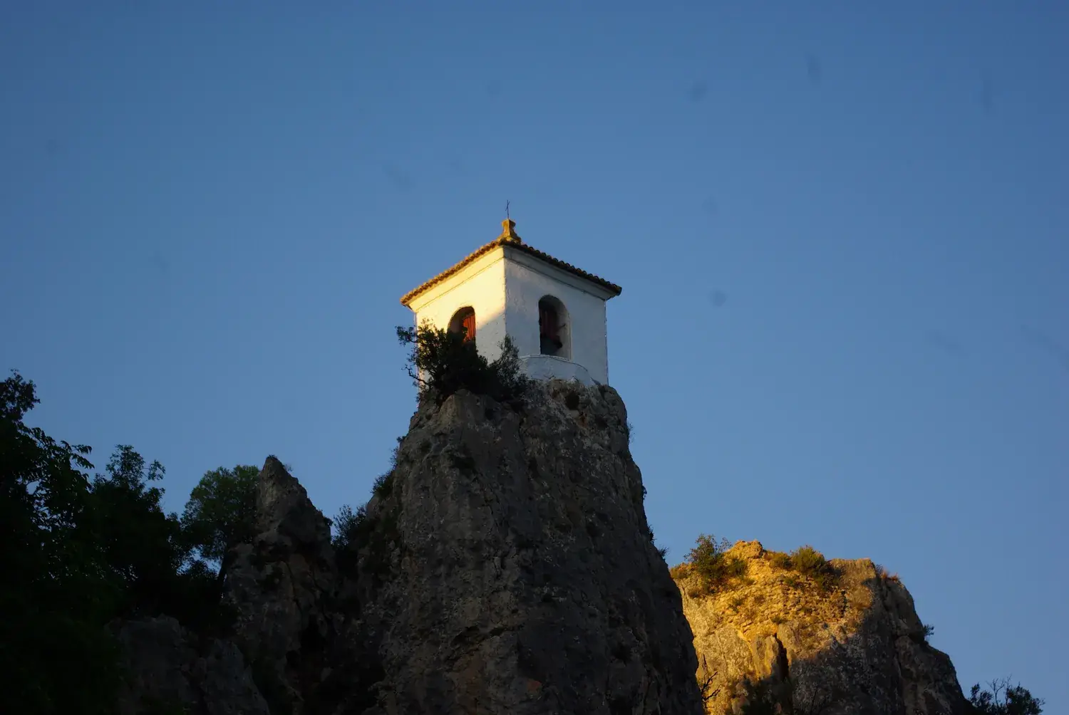 Le campanile blanc de Guadalest au sommet d’un piton rocheux au coucher du soleil