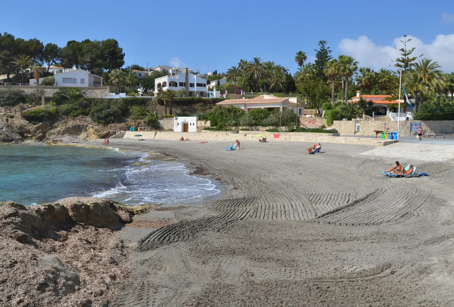 The sandy beach of Cala de la Fustera in Benissa, surrounded by pines and houses