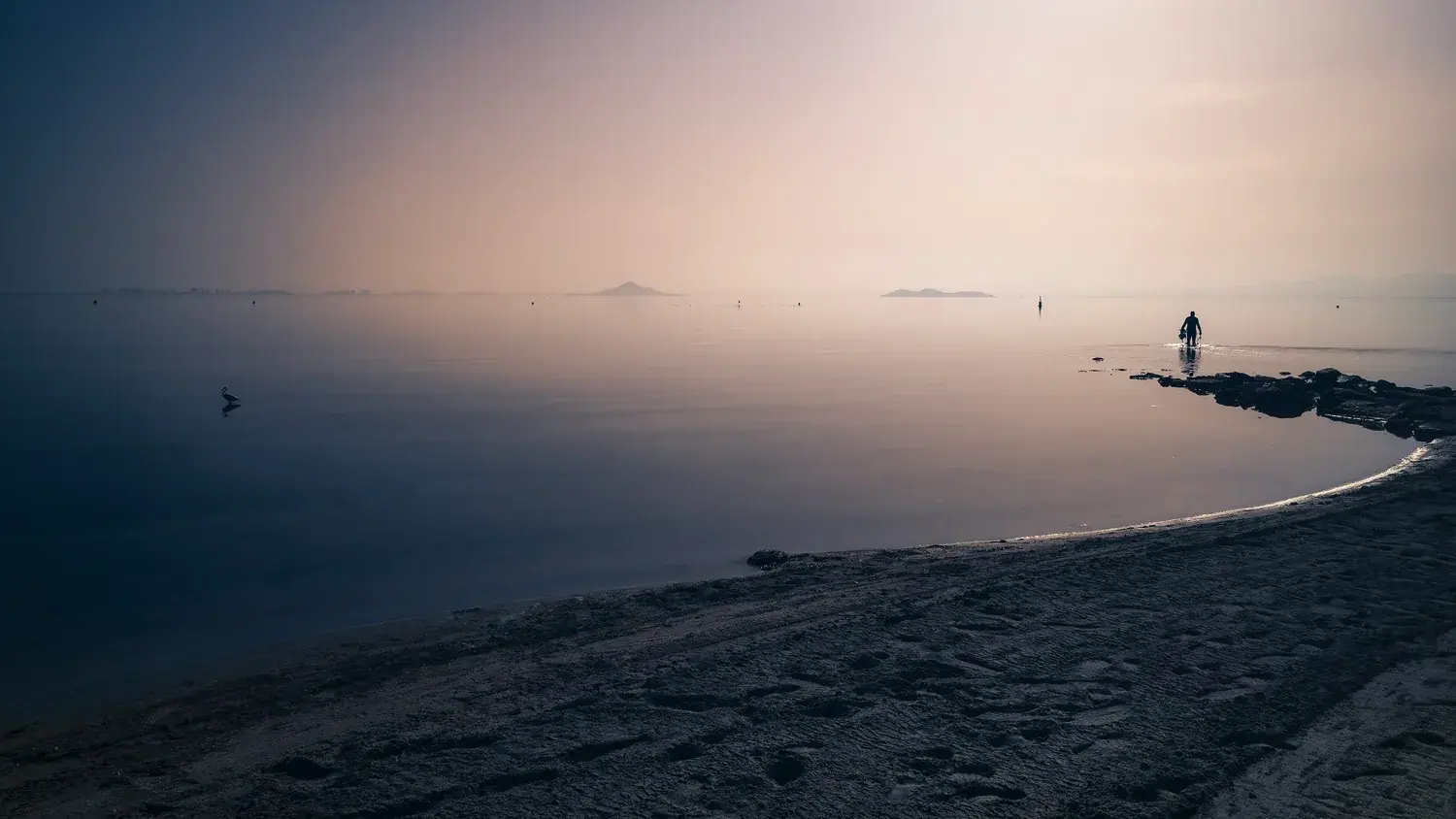 La Mar Menor calme au coucher du soleil, eau lisse et horizon brumeux
