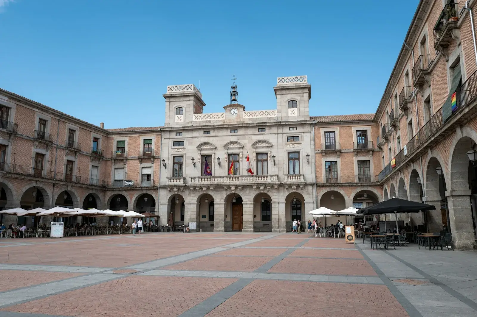 Plaza mayor ensoleillée bordée d’arcades devant l’hôtel de ville