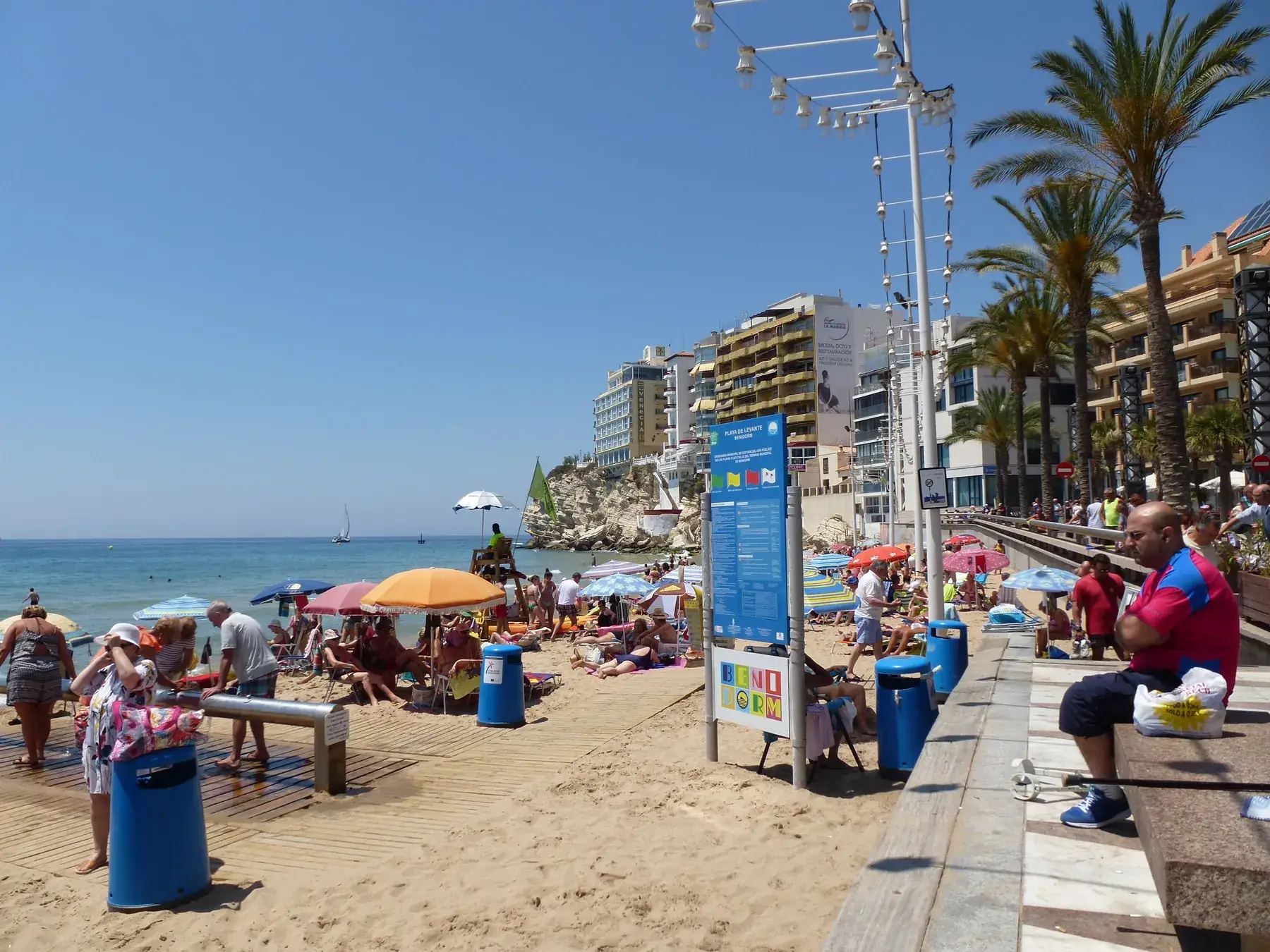 Familles se promenant le long de la plage de Levante à Benidorm, parasols et mer bleue