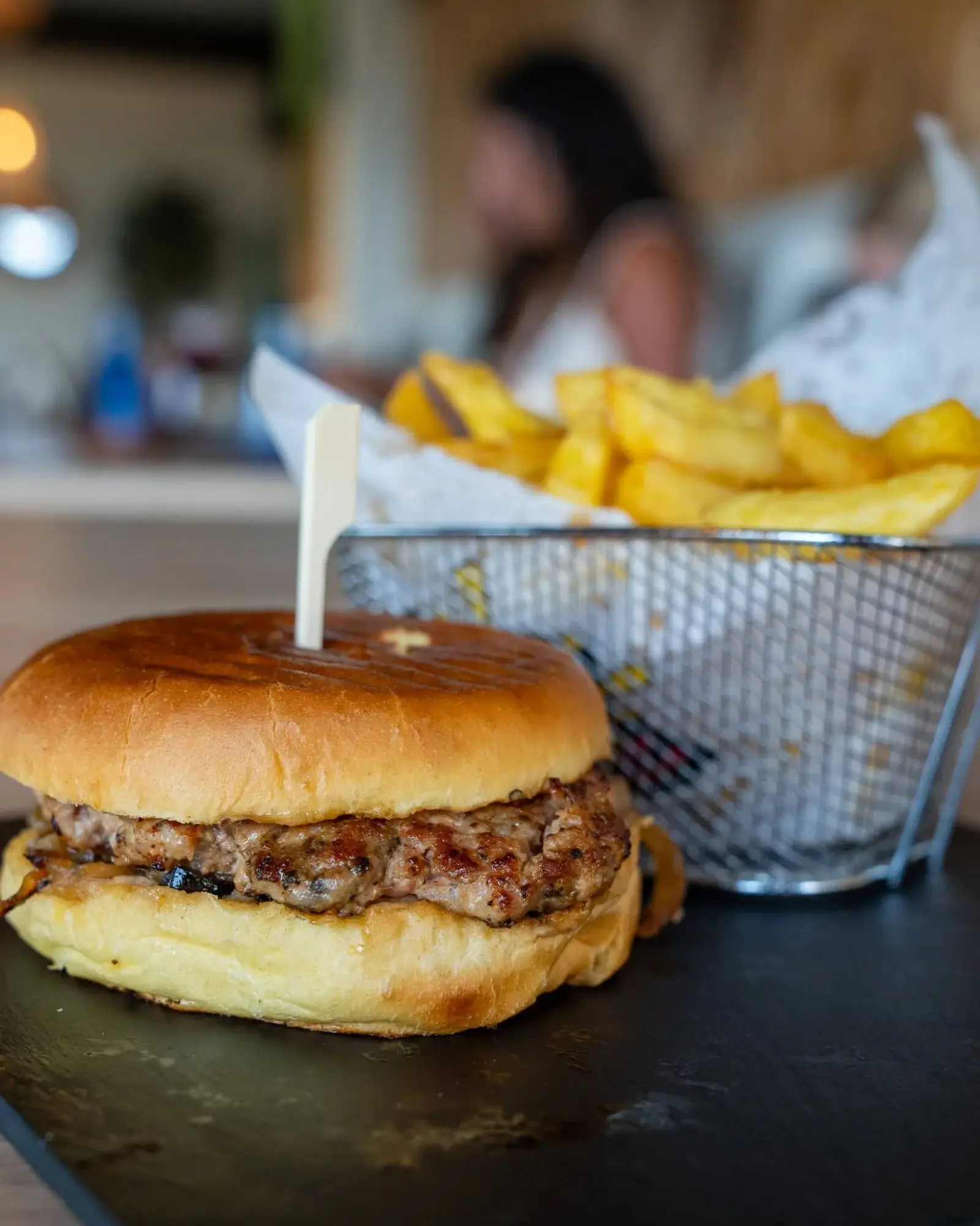 Burger dans un pain brioché grillé et panier de frites belges dorées chez Hola Patatas, à Ciudad Quesada