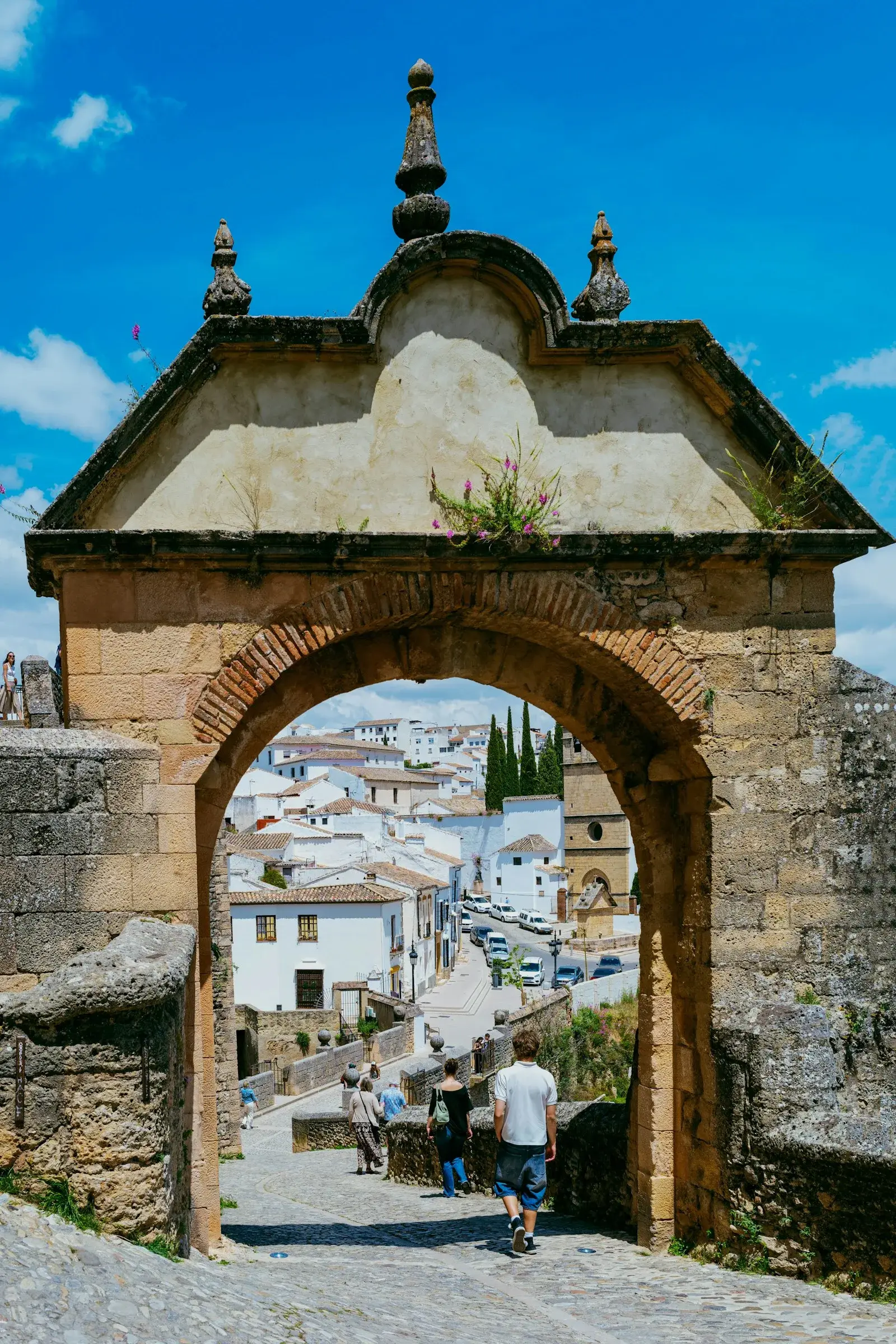 Arche de pierre ouvrant sur un village aux maisons blanches