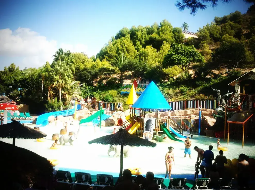 Zone de jeux d’eau pour enfants d’Aqualandia, avec toboggans colorés sous les pins