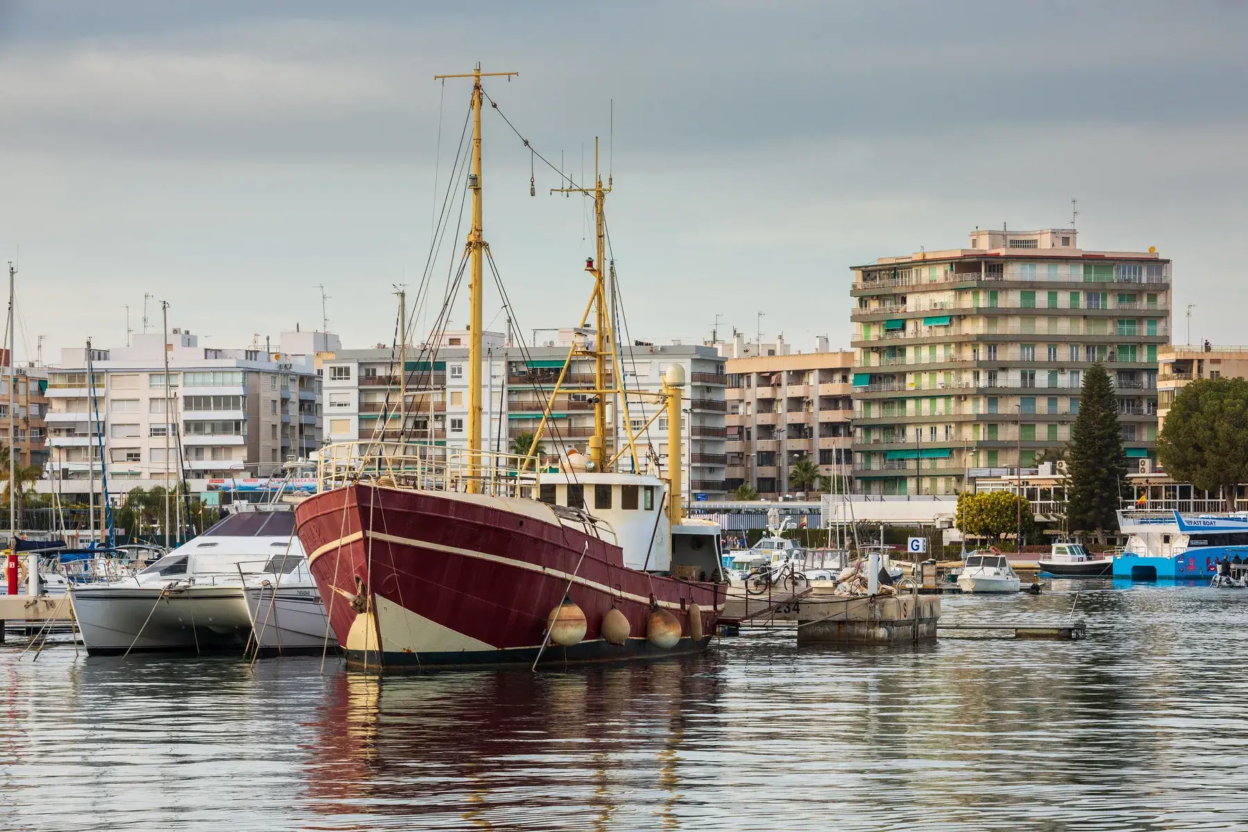 Le port de plaisance de Santa Pola, ses bateaux amarrés et un vieux voilier de pêche